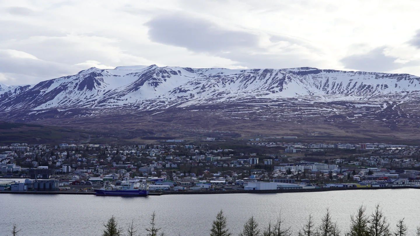 A wide view of Akureyri and its harbour below the snow-covered mountain slopes