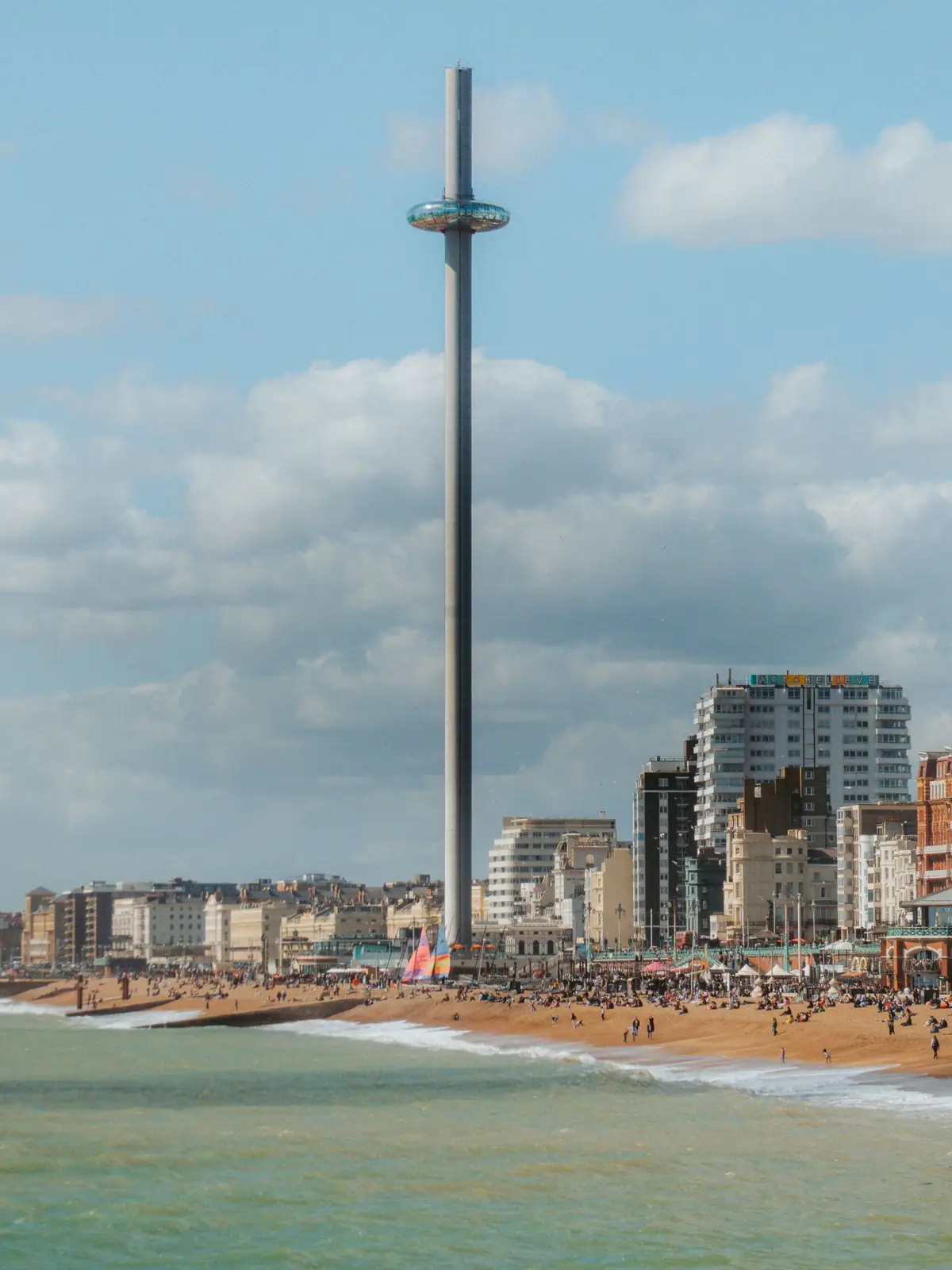 Brighton i360 tower above a busy beach