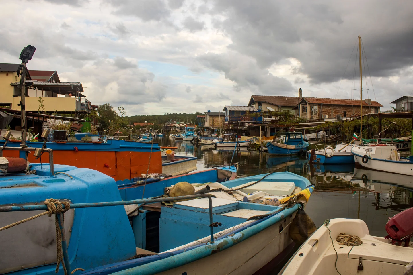 Blue fishing boats moored beside waterside houses in Chengene Skele near Burgas