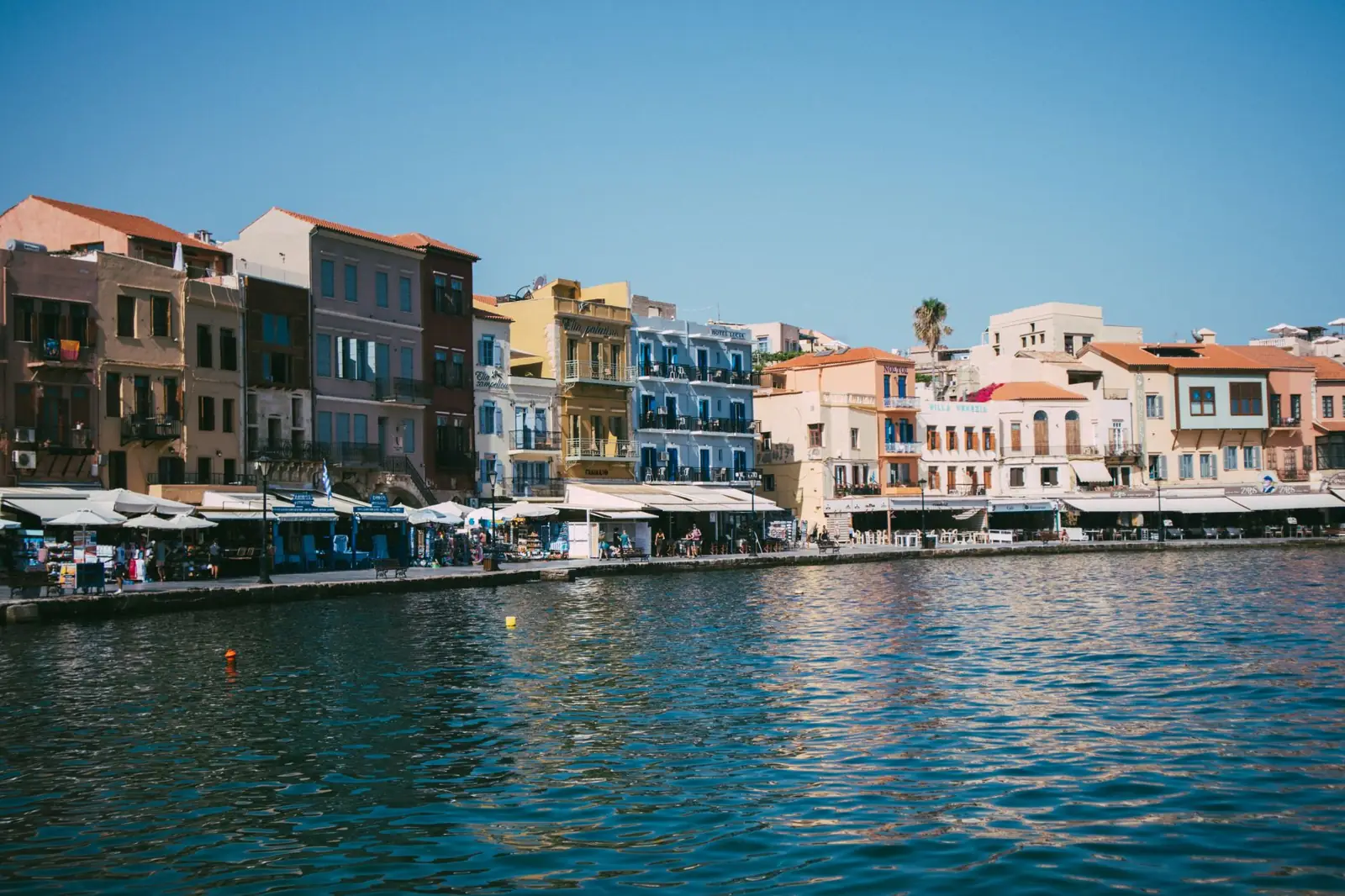 Colourful buildings and restaurant terraces along Chania’s harbour