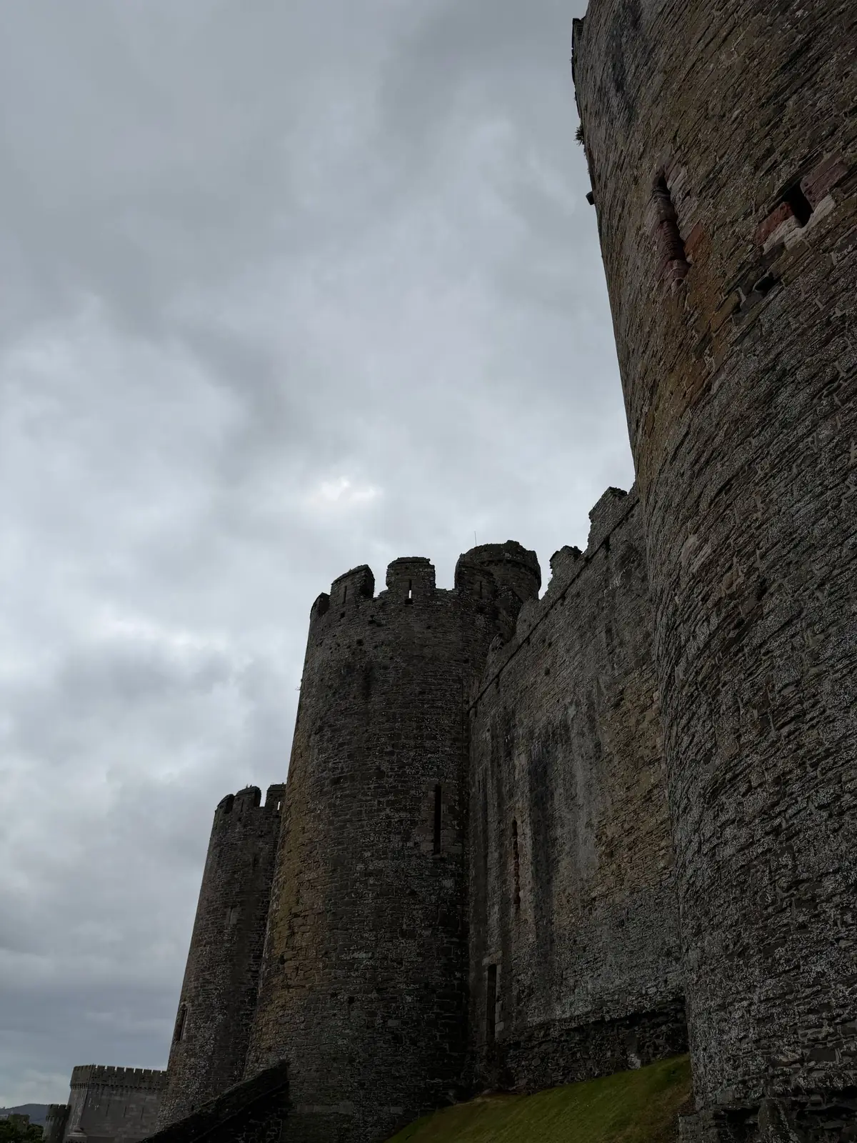 Conwy Castle’s round towers and defensive walls beneath a cloudy sky