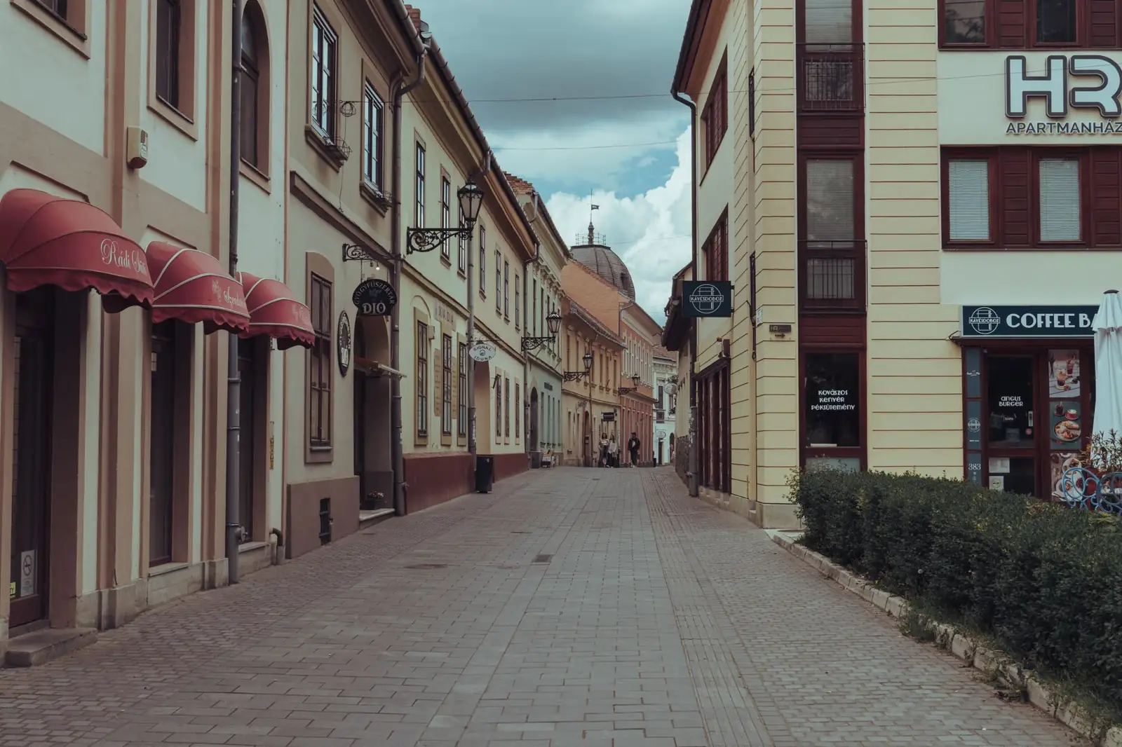 Eger’s paved Jókai Mór Street with historic façades and the HR Apartmanház corner sign