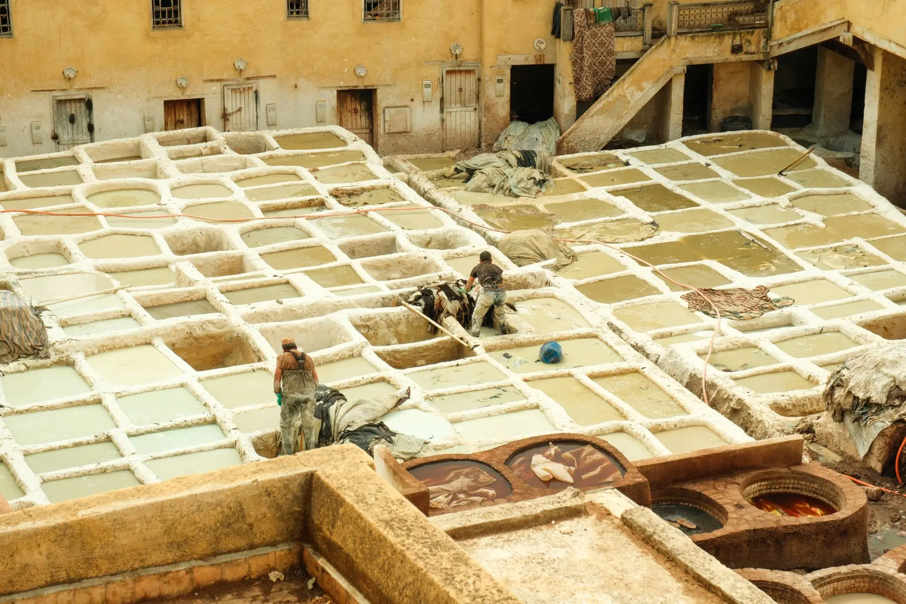 A view of traditional leather tanneries in Fes, Morocco with workers in action.