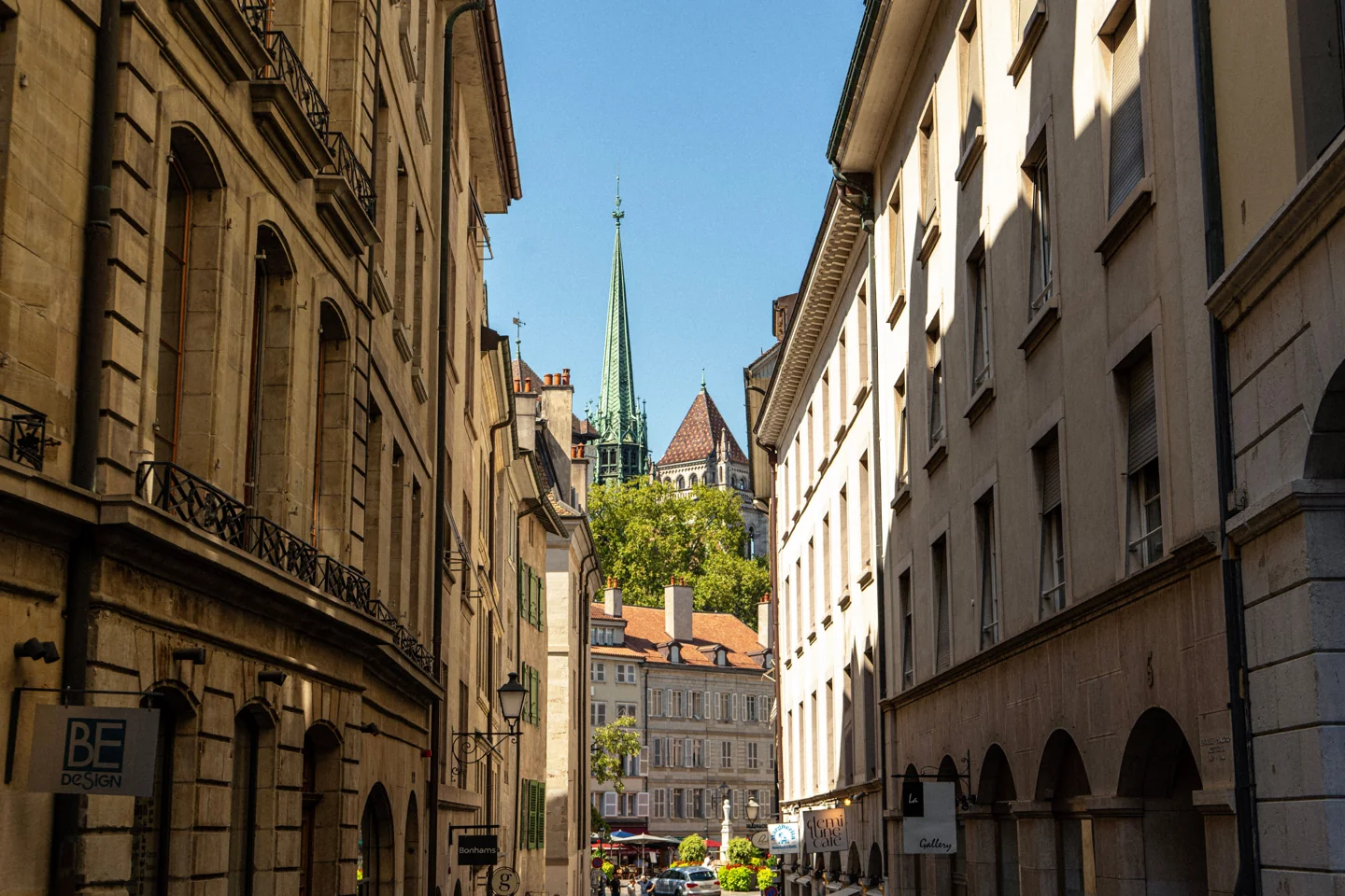 Geneva old-town street leading towards Saint-Pierre Cathedral’s green spire
