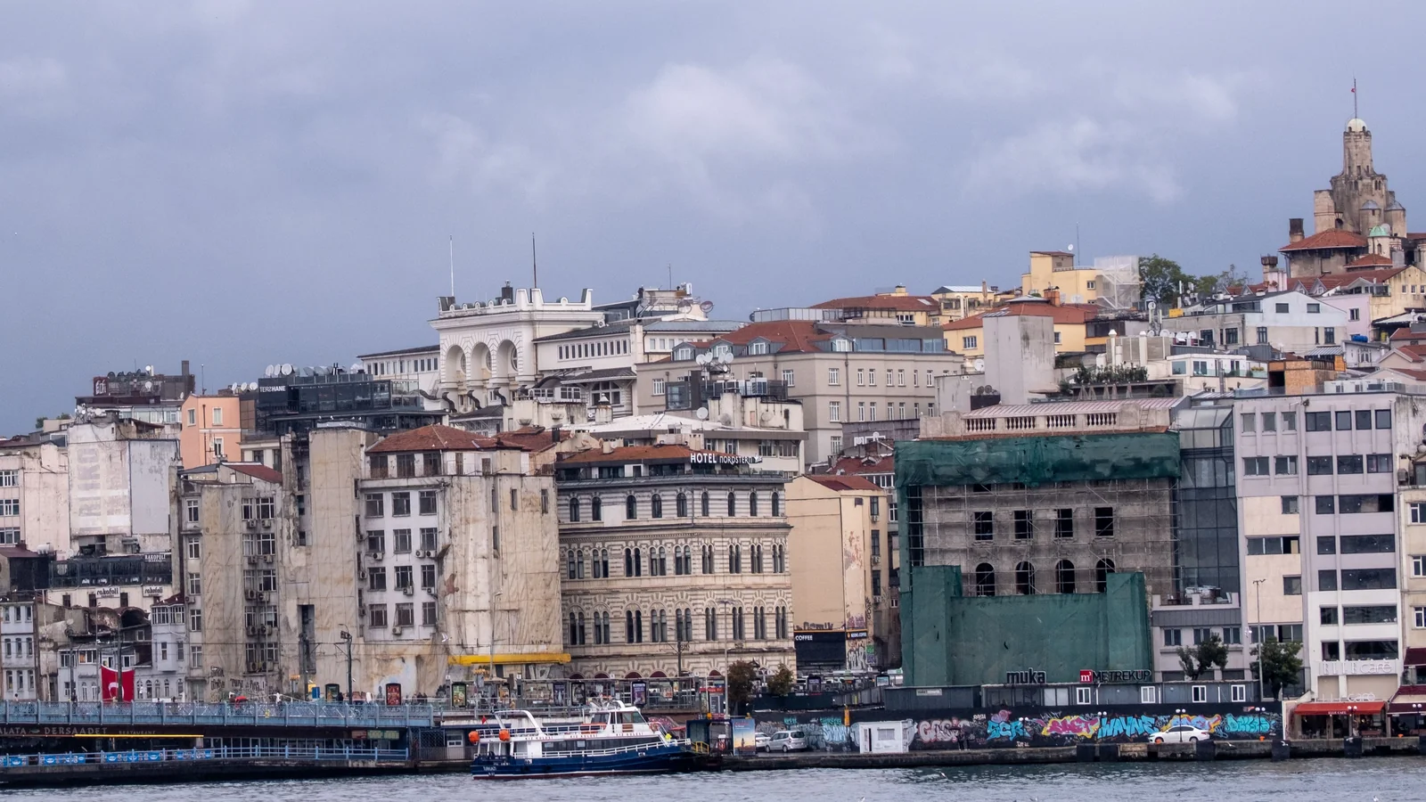 Waterfront buildings on the Karaköy side of Istanbul beneath a cloudy sky.