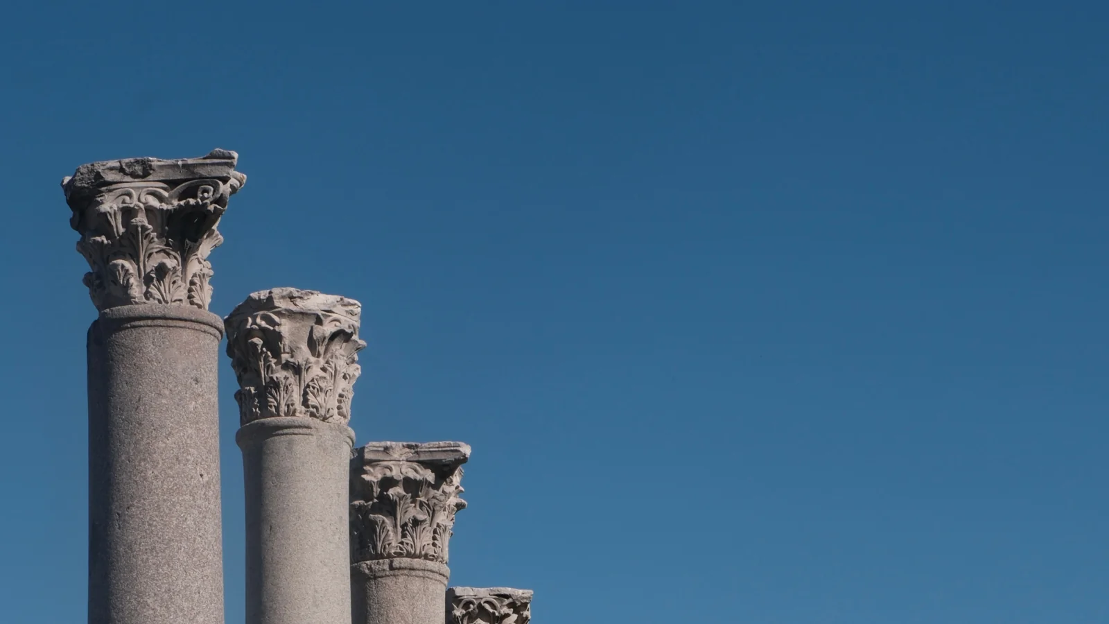 Carved capitals on the colonnade of Smyrna’s Agora against a blue İzmir sky.