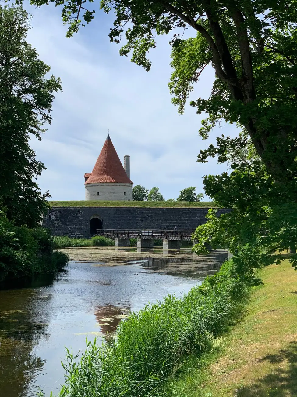 Kuressaare’s castle moat and outer fortification tower framed by leafy park trees