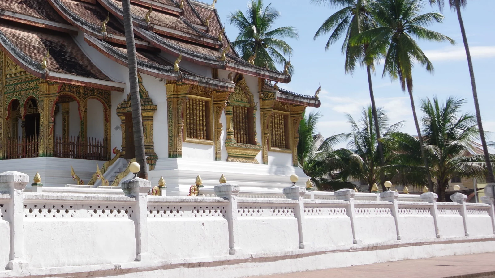 Ho Pha Bang’s layered roof, gilded porch and white perimeter wall in Luang Prabang.