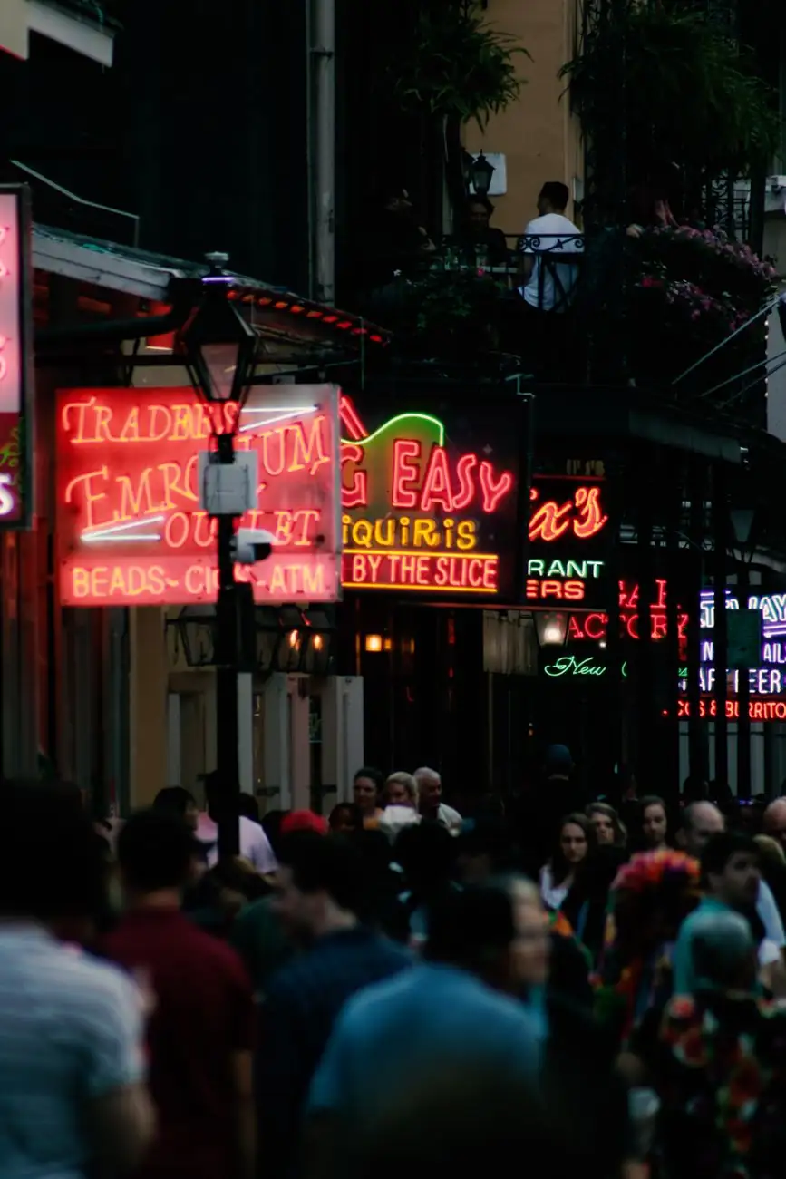 Crowds and neon shopfront signs on Bourbon Street in New Orleans at night