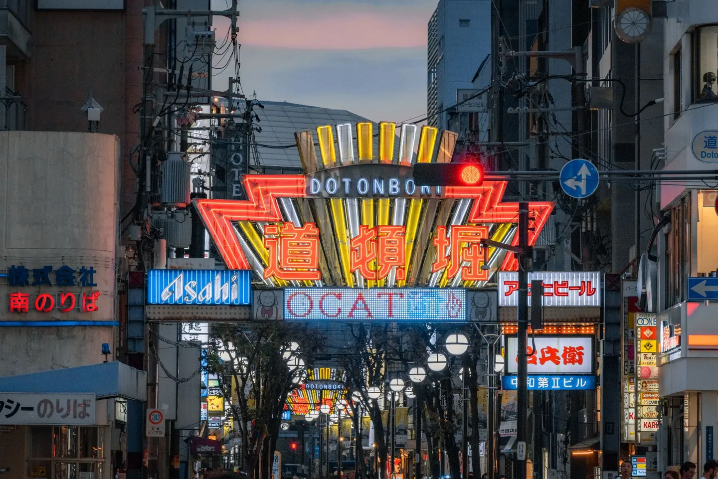 Dotonbori’s illuminated entrance sign and shopping street at dusk
