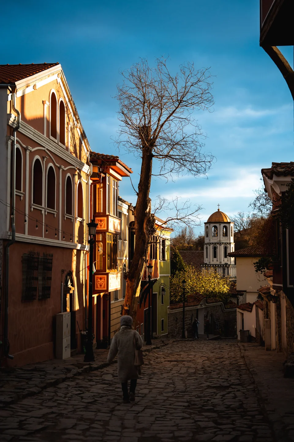 Sunlit cobbled Old Town street in Plovdiv with colourful houses and a church bell tower