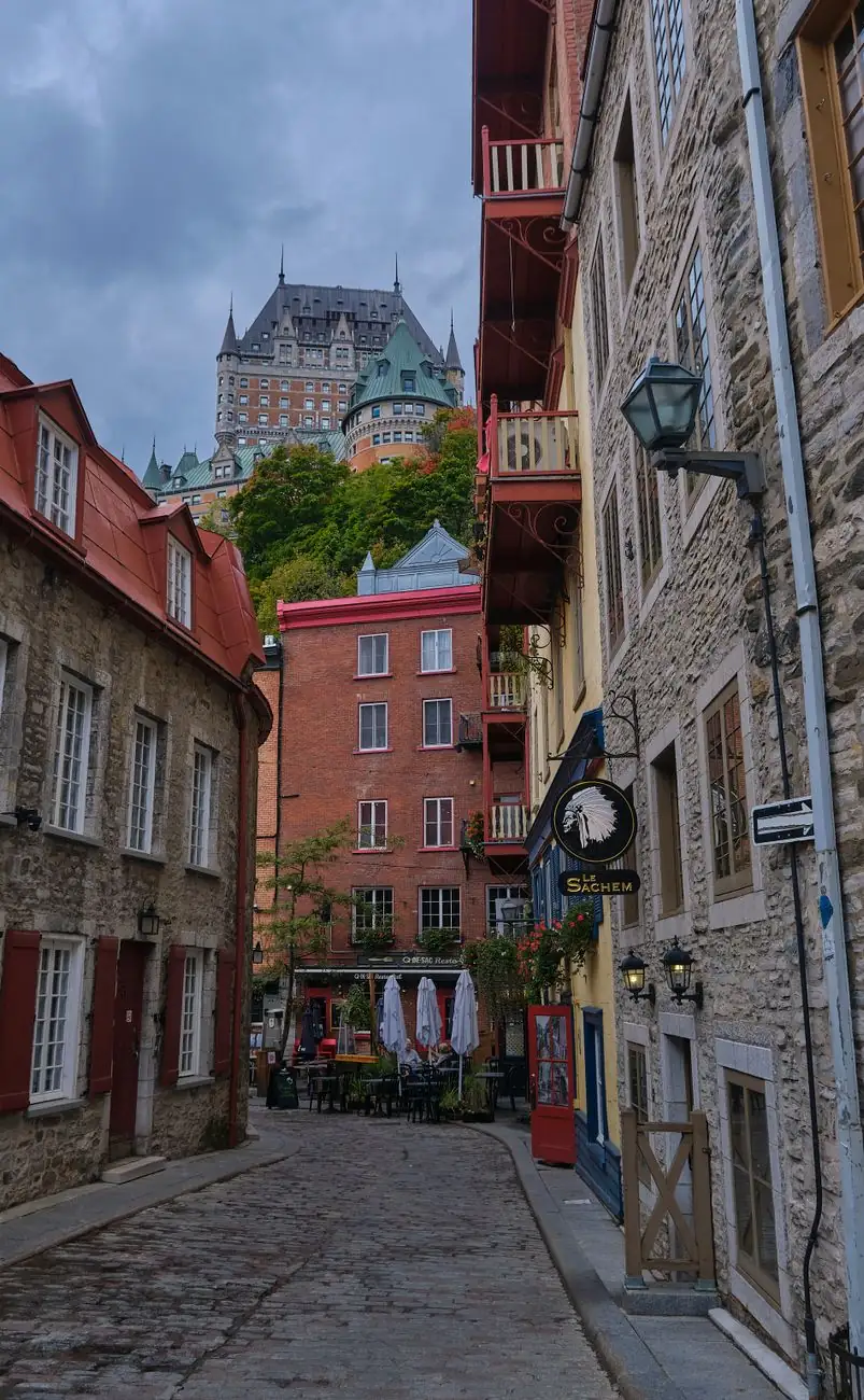 Stone buildings on a narrow Old Québec lane with Château Frontenac rising beyond