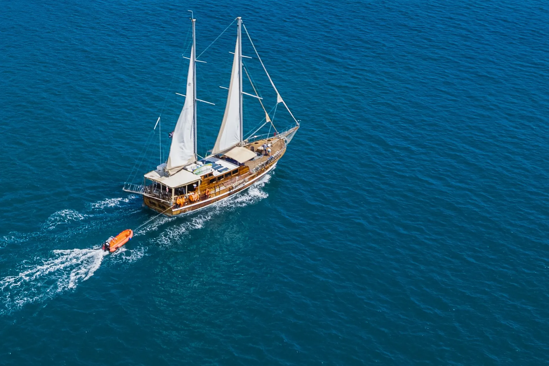 A two-masted wooden sailing vessel off the wooded coast near Quepos