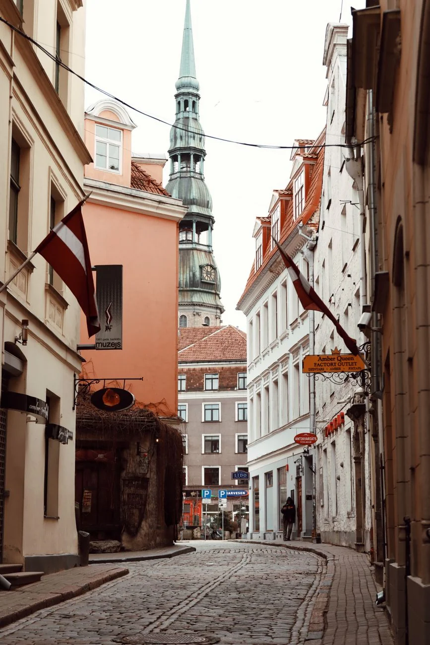 St Peter’s Church spire above a cobbled Riga Old Town street and colourful façades