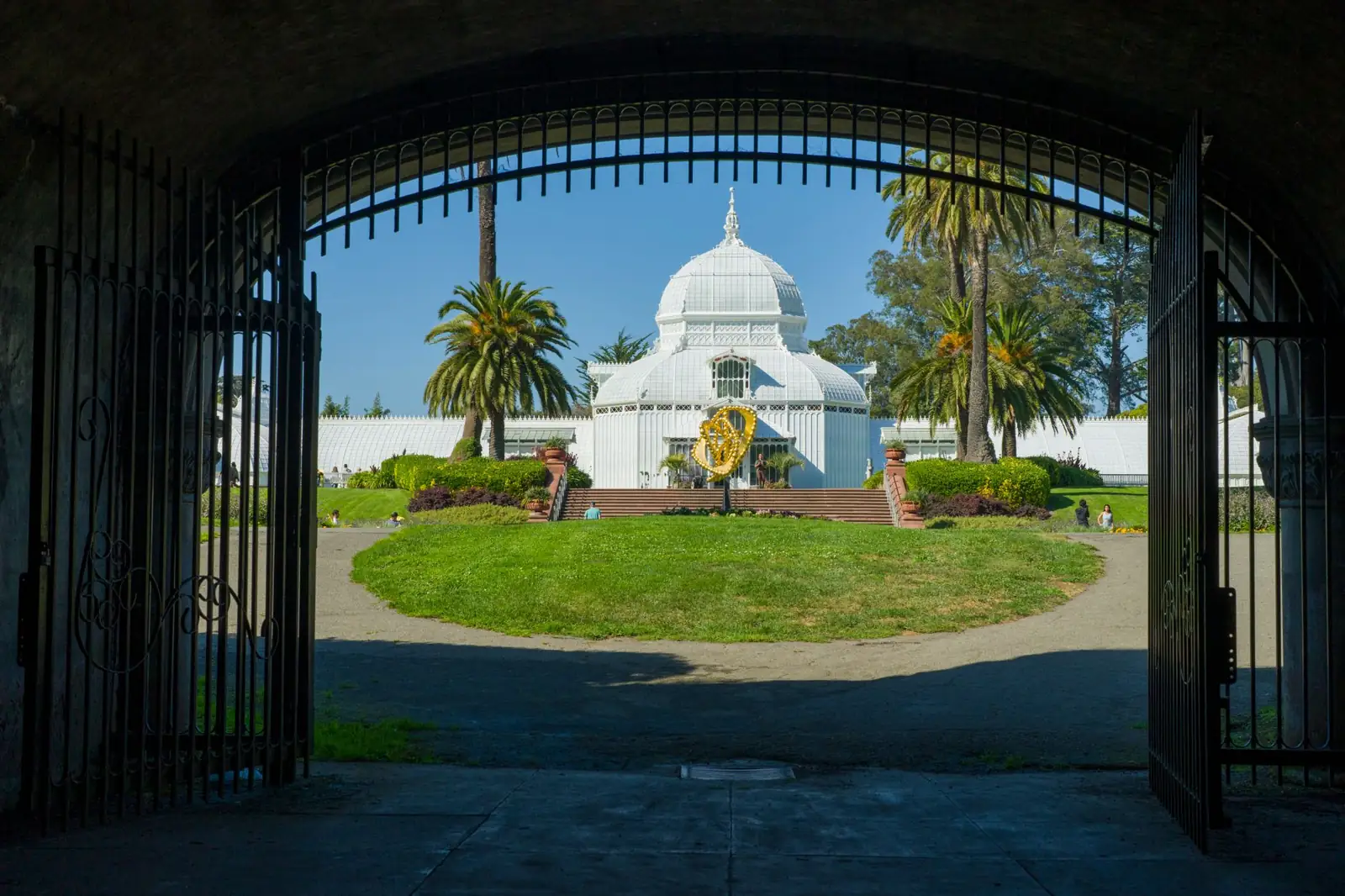 The white domed Conservatory of Flowers in Golden Gate Park viewed through entrance gates