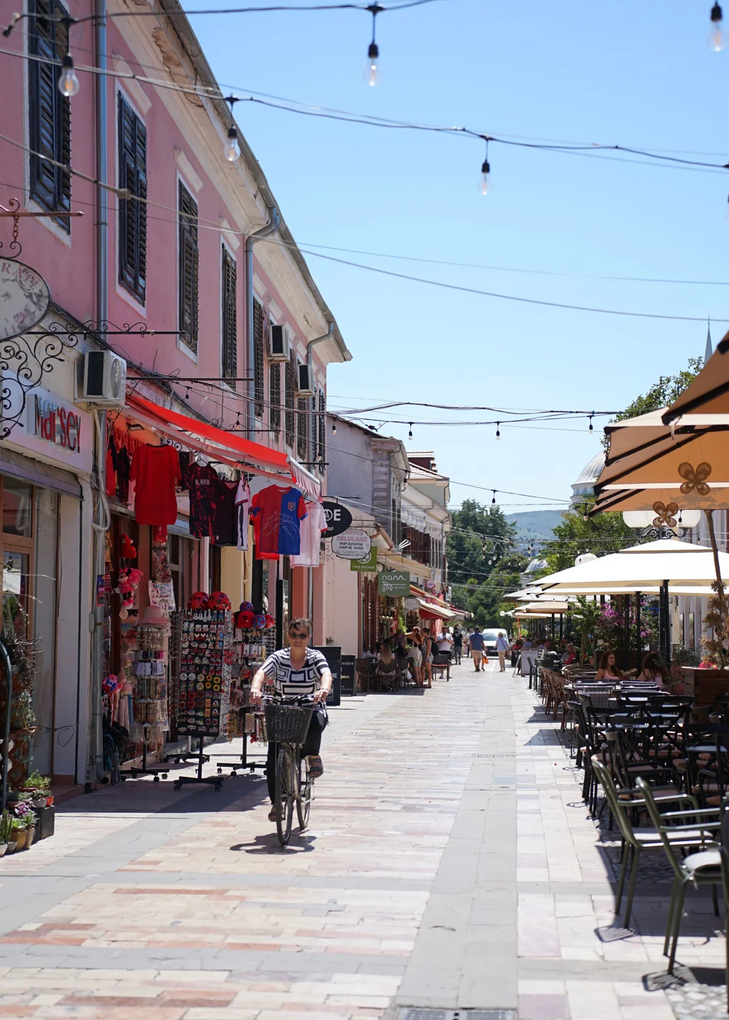 Cyclist and café tables along Shkodër’s Kolë Idromeno pedestrian street