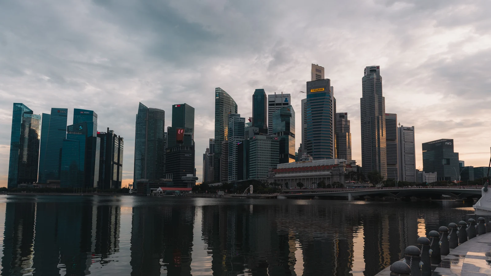Singapore’s downtown buildings and waterfront reflect the evening sky across Marina Bay.