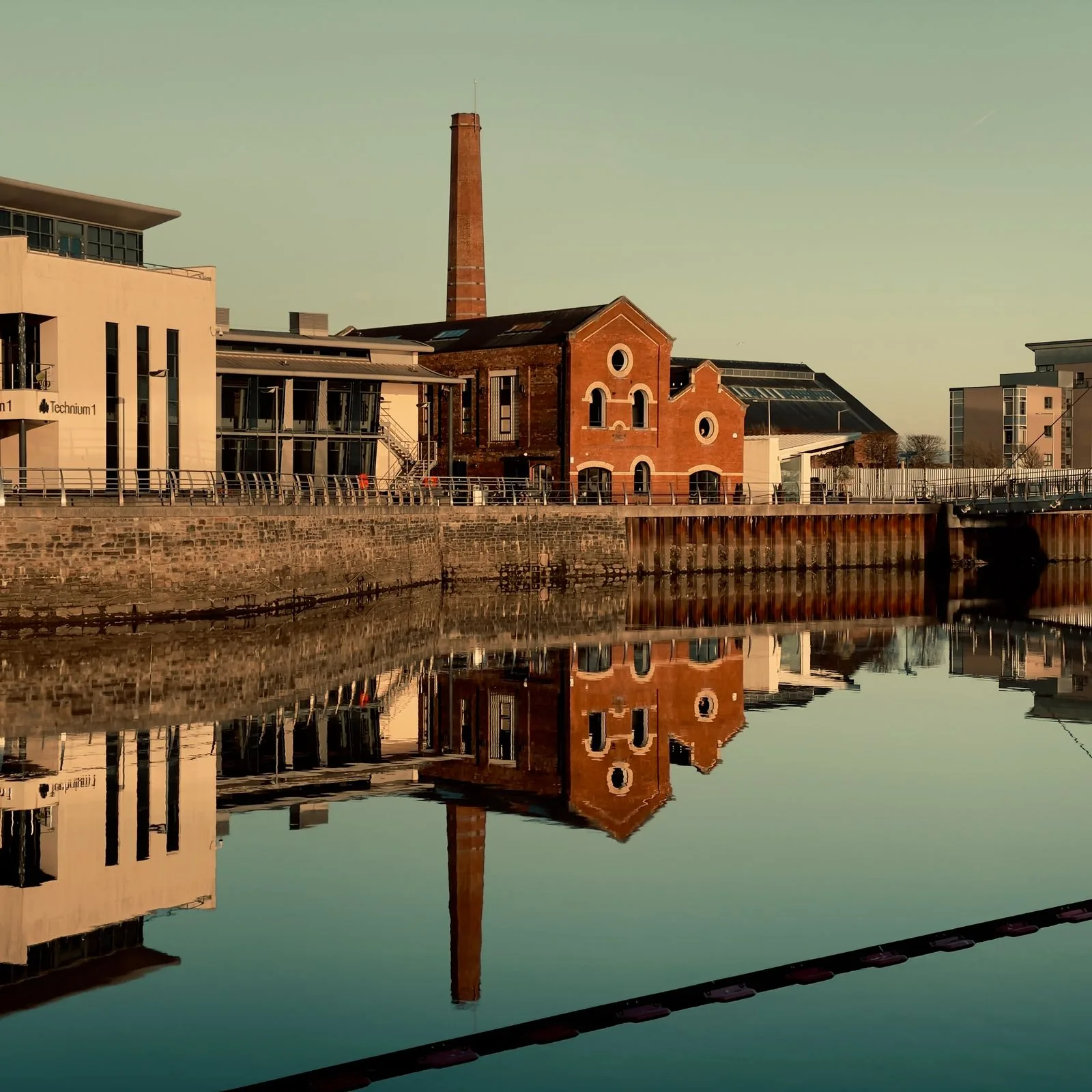 Historic industrial waterfront buildings reflected in Swansea's water