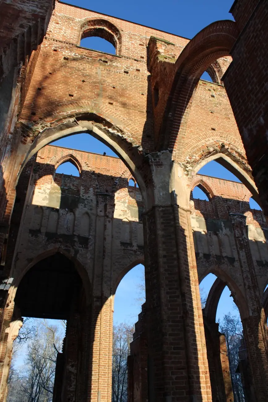 Pointed red-brick arches and surviving walls of Tartu Cathedral’s roofless nave against a blue sky