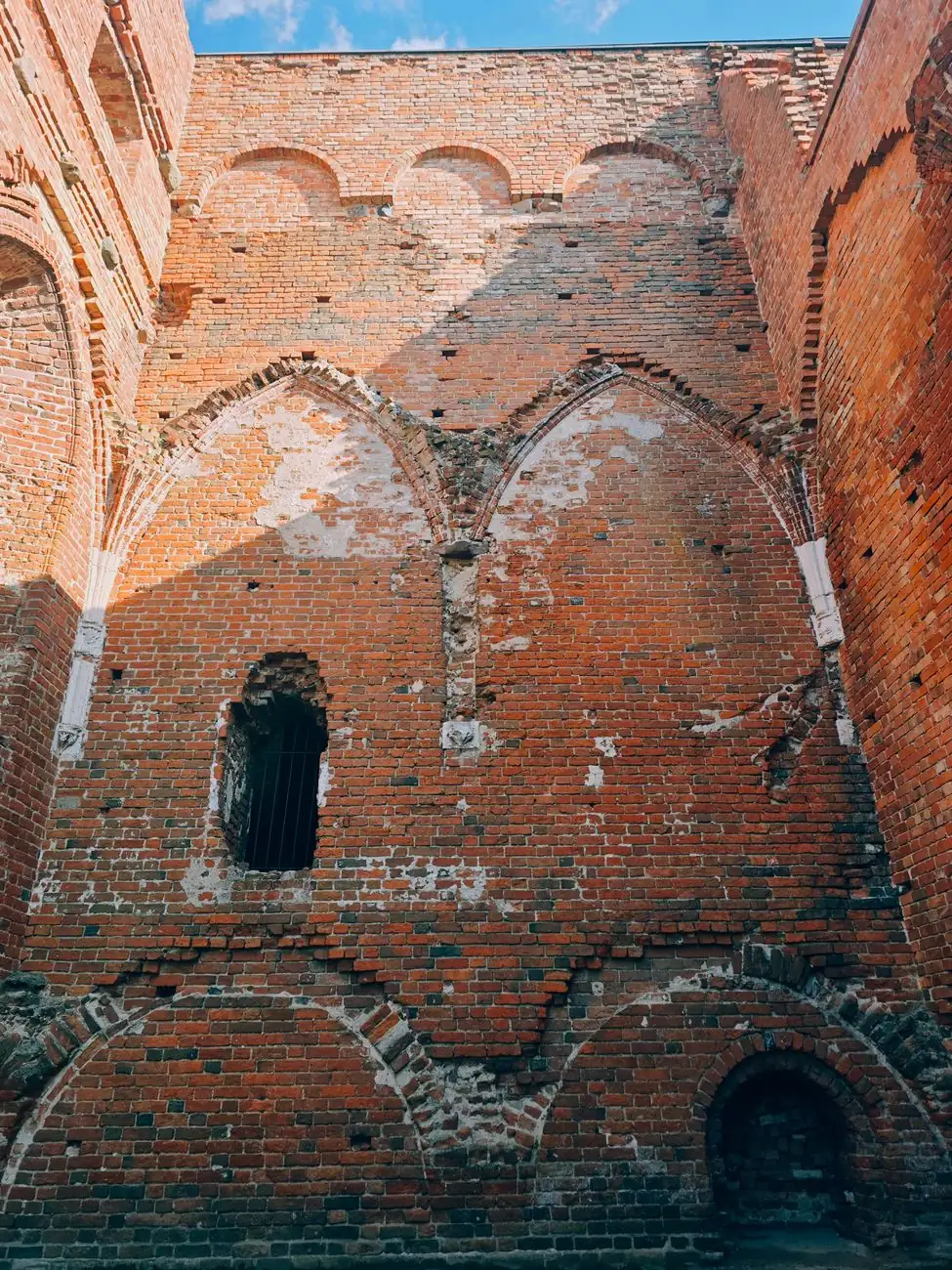 Red-brick Gothic arches and old window openings inside the roofless ruins of Tartu Cathedral