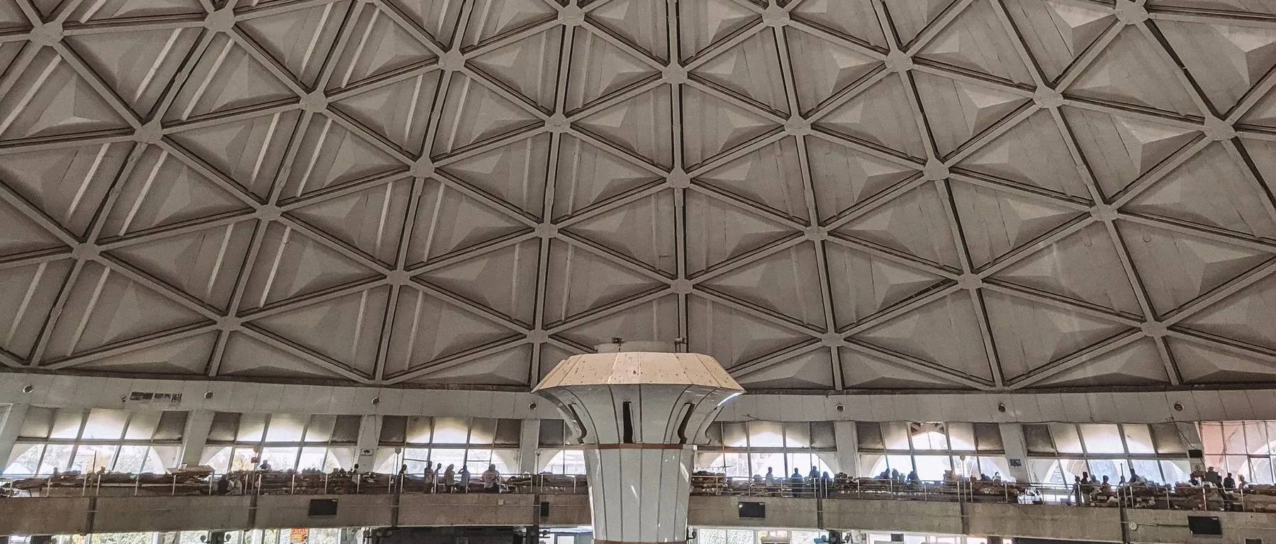 Geometric concrete ribs and market counters inside Chorsu Bazaar’s domed hall in Tashkent