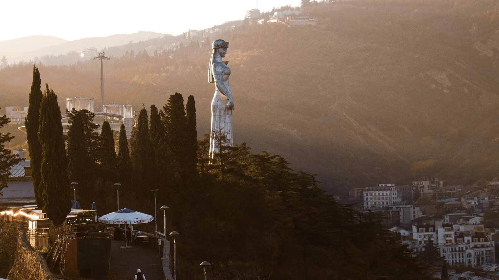 The Mother of Georgia statue on the Sololaki ridge above Tbilisi in warm evening light.