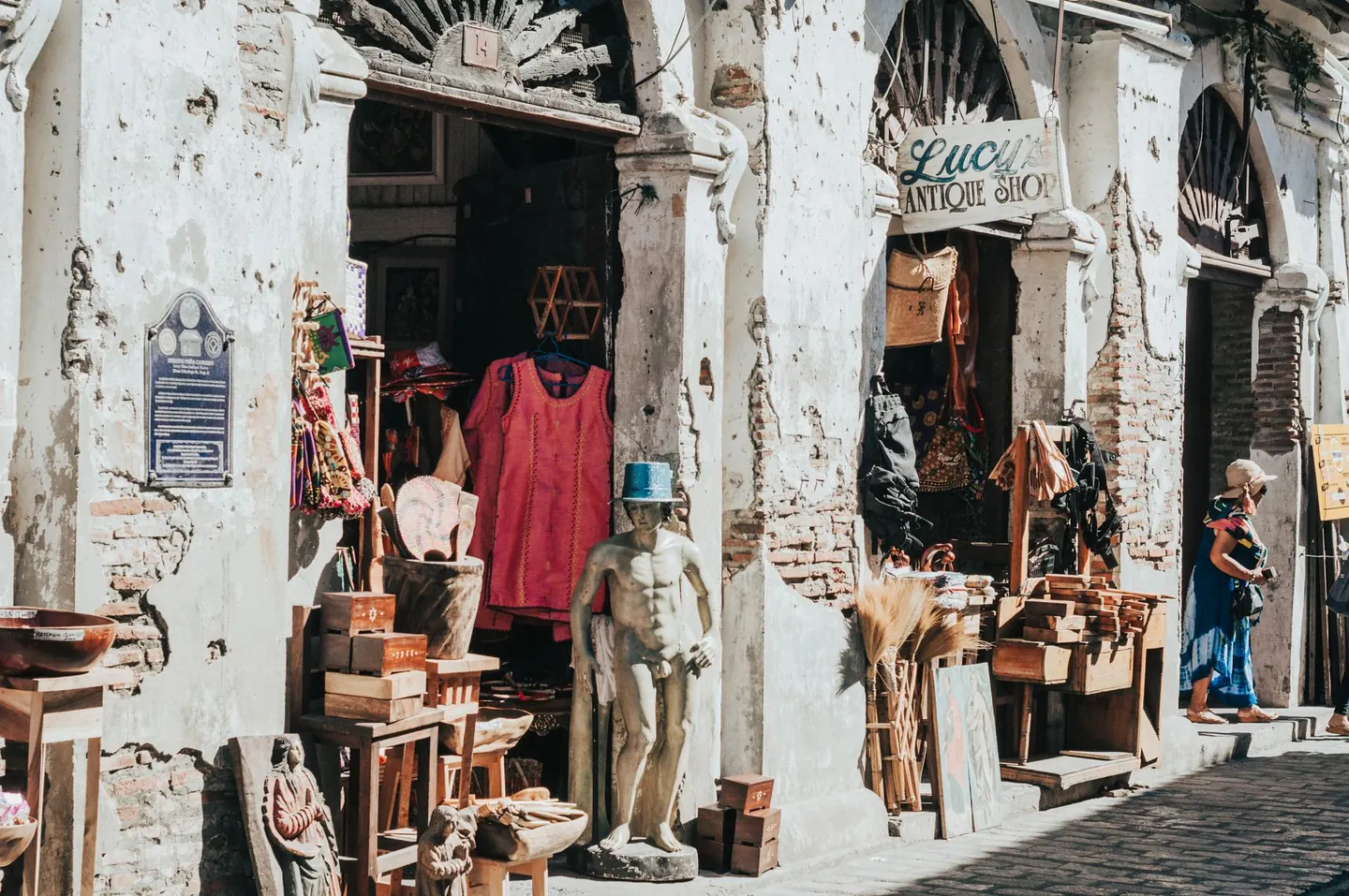 An antique shop with timber shutters and goods displayed beneath an old masonry façade on Calle Crisologo in Vigan