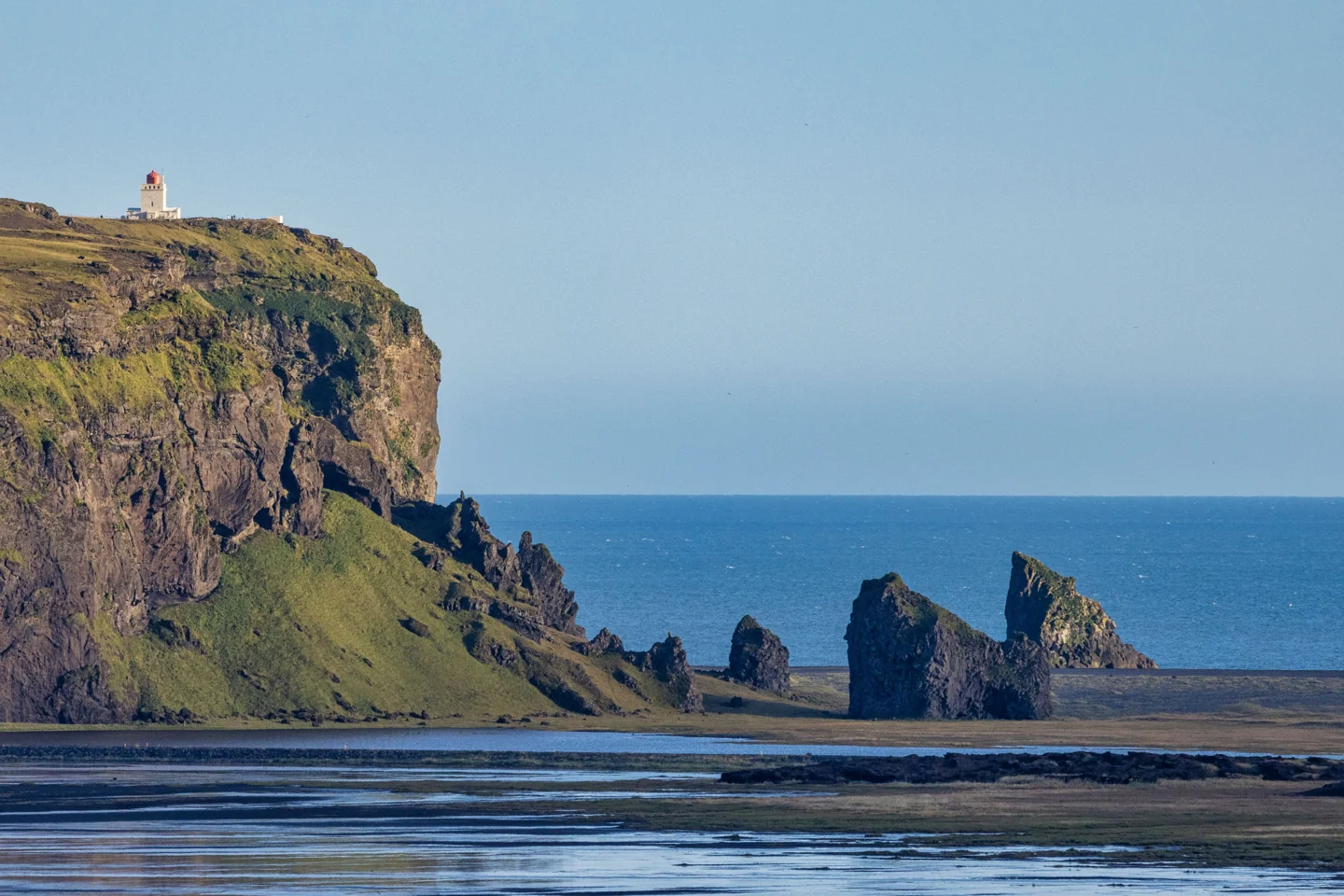 Dyrhólaey’s coastal headland and lighthouse above dark beaches and offshore rocks