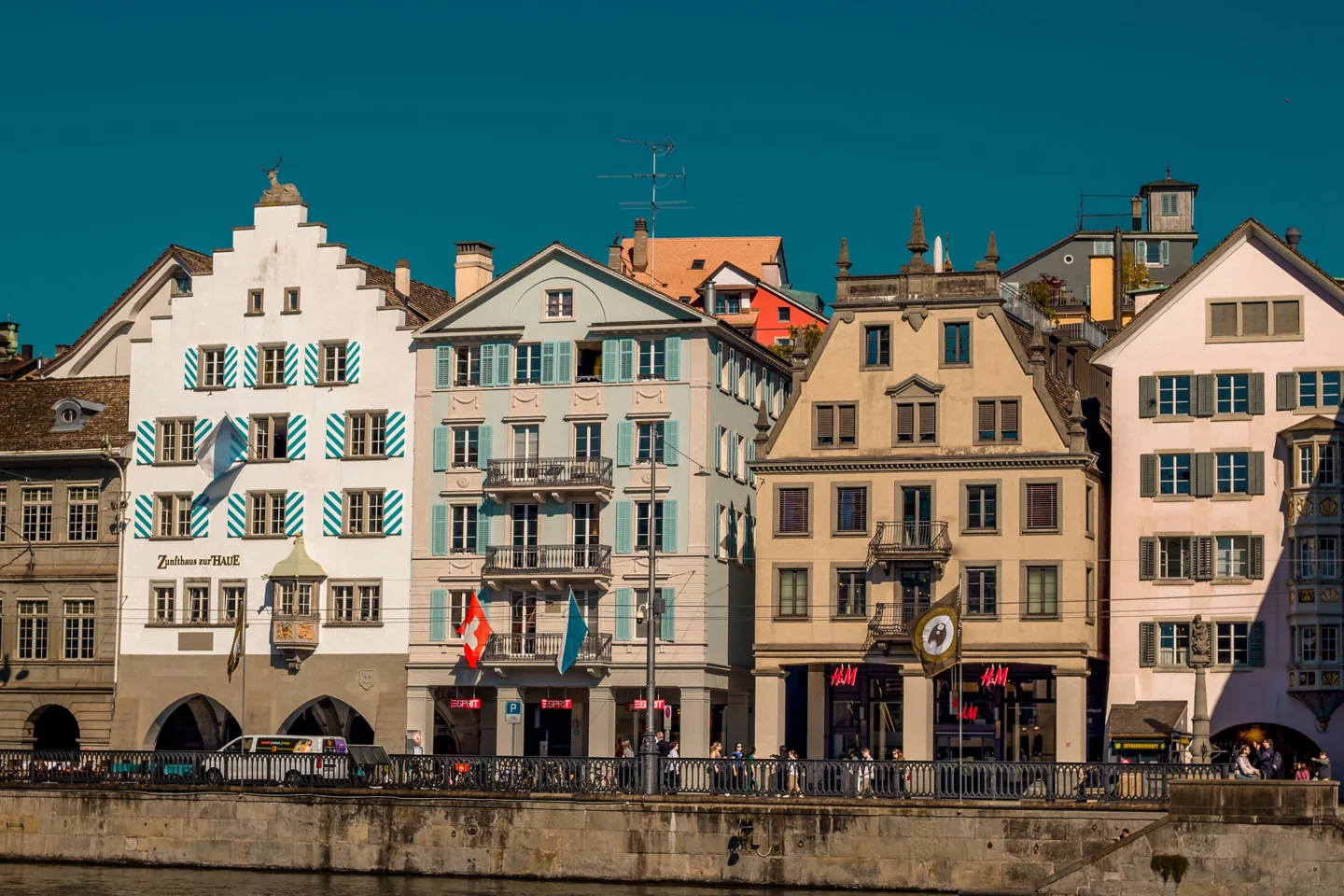 Historic riverside facades and Swiss flags in Zürich’s old town