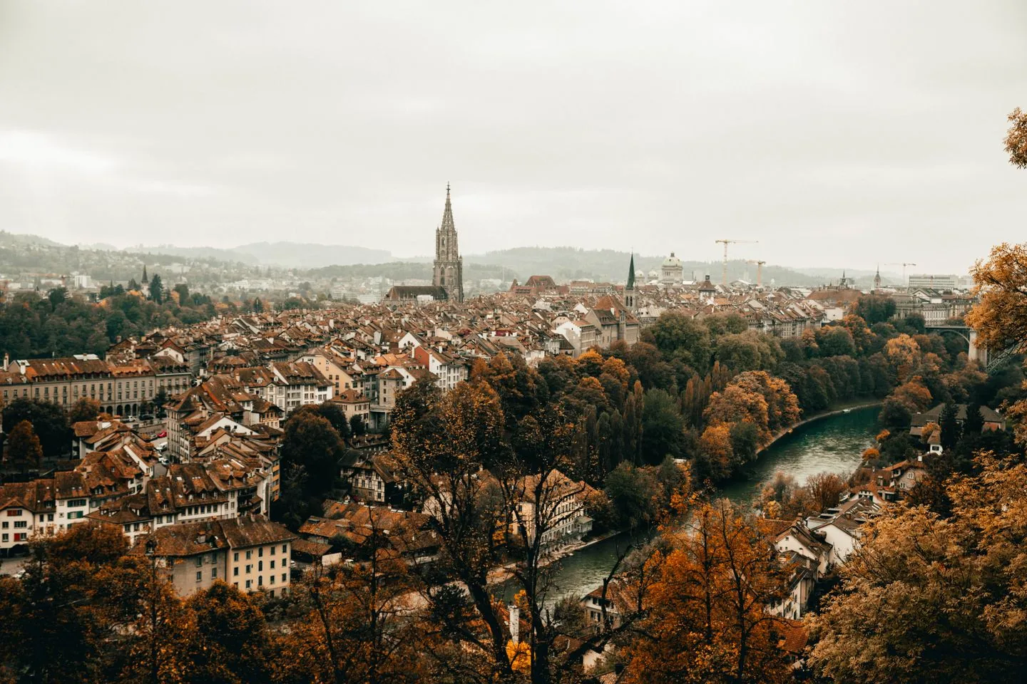Bern’s cathedral, old-town rooftops and River Aare surrounded by autumn trees