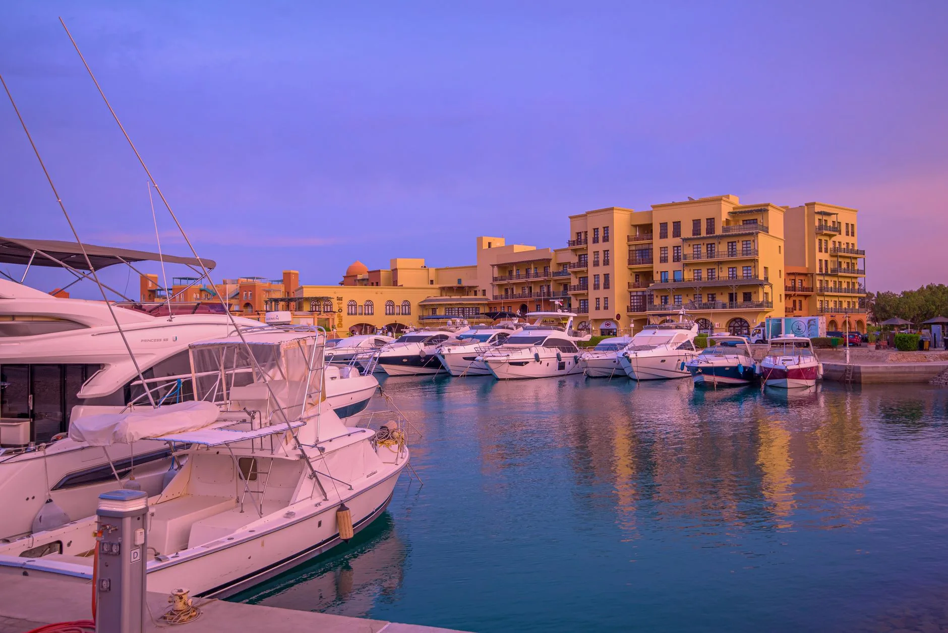 Yachts moored beneath the colourful waterfront buildings of Hurghada Marina at dusk
