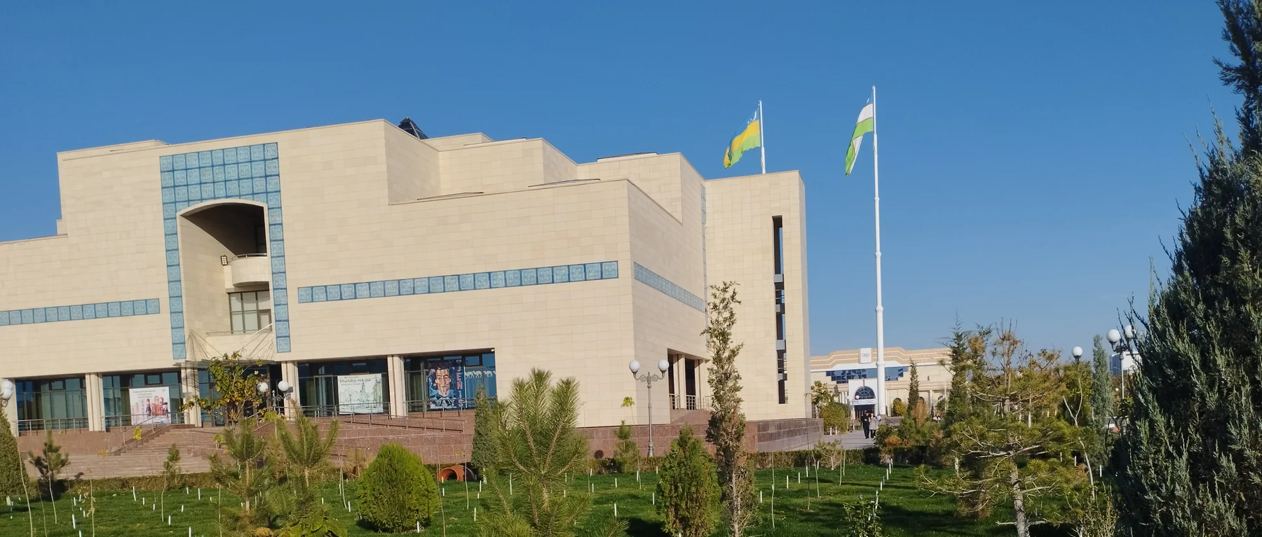 Beige facade and blue tile bands of the Savitsky Museum in Nukus, with Karakalpakstan and Uzbekistan flags