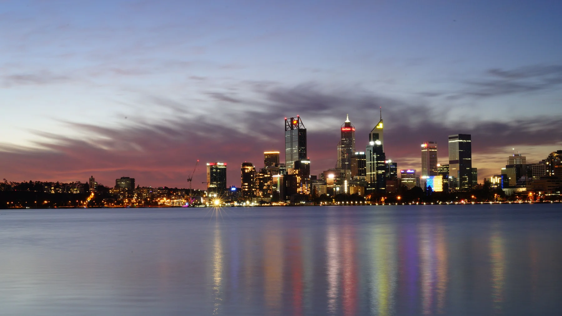Perth’s illuminated city skyline across the Swan River at dusk