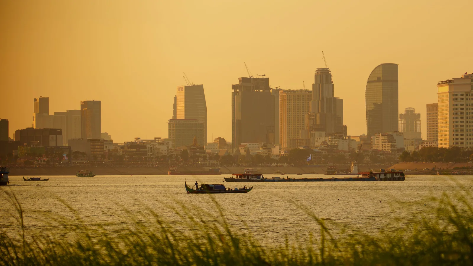 Phnom Penh’s riverfront skyline and boats at sunset.