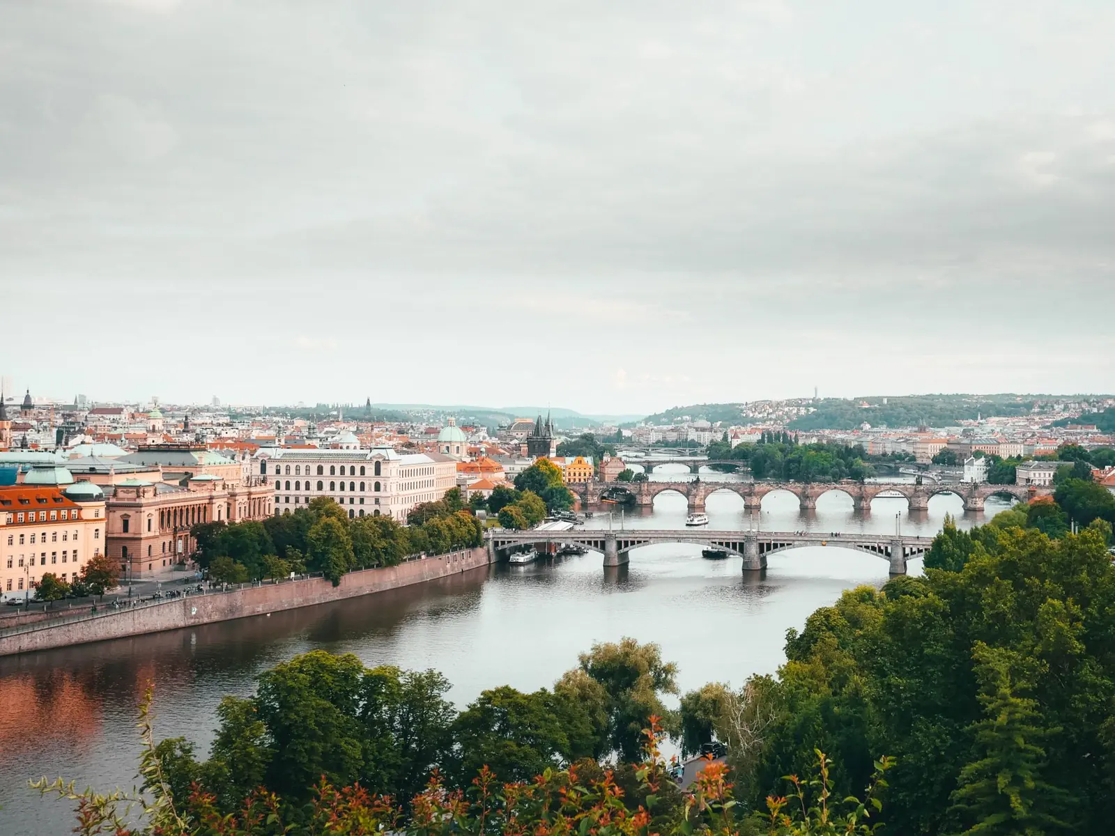 The Vltava and successive Prague bridges, with historic waterfront buildings and trees