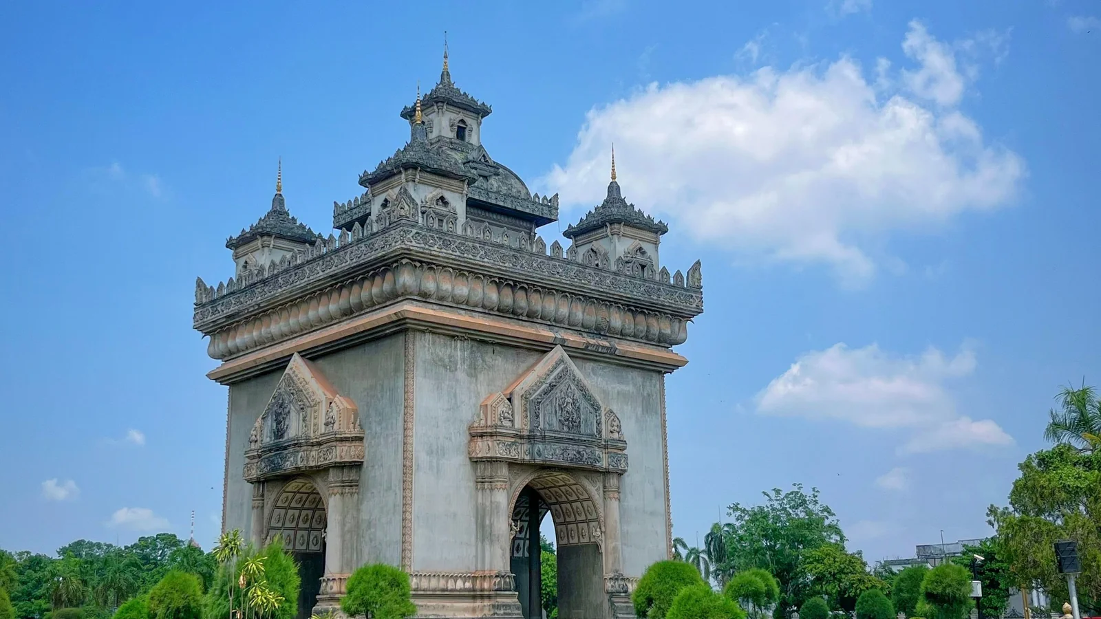 Patuxai’s tiered towers and arched stone facade above the gardens in Vientiane.