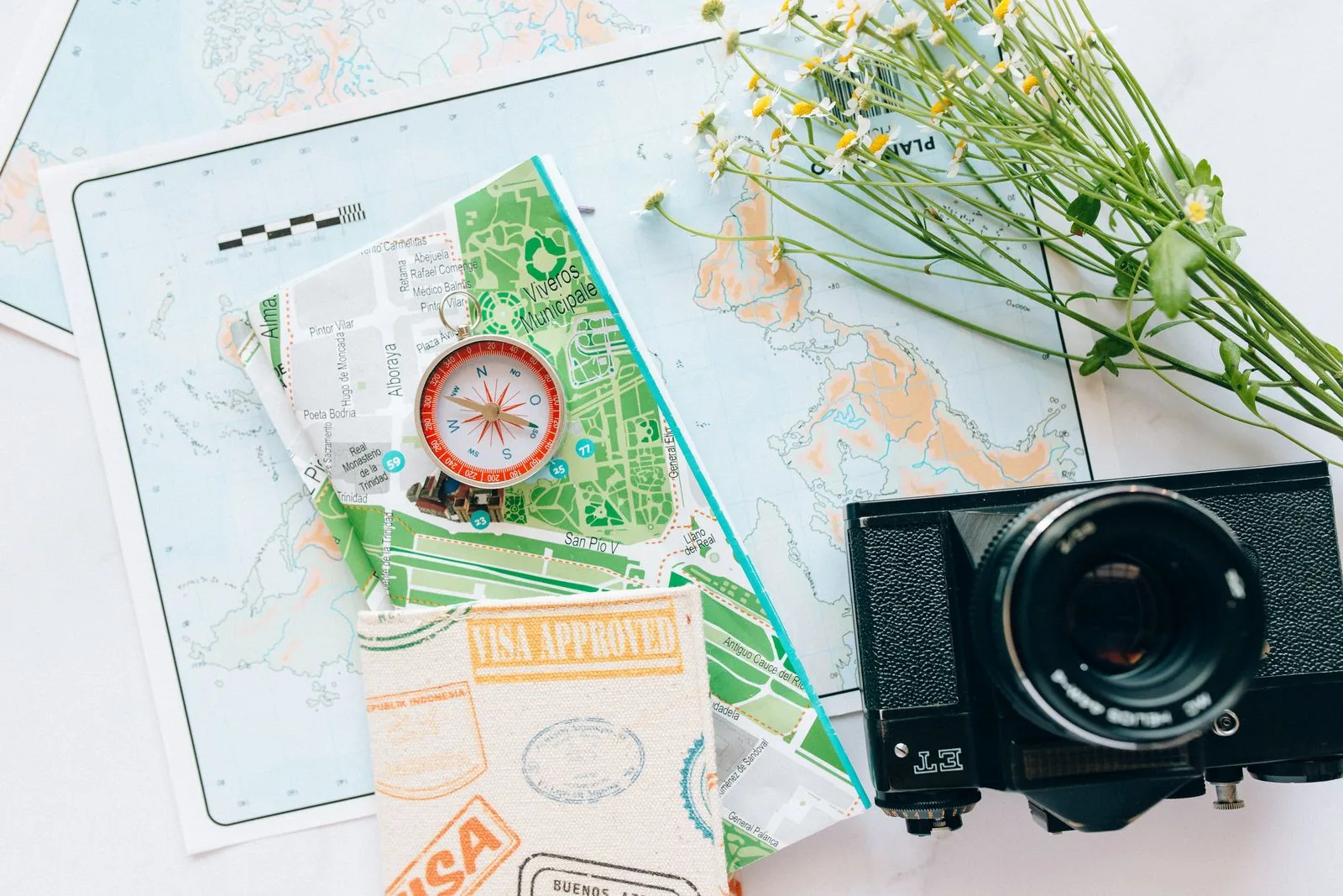 Travel maps, compass and camera arranged for planning a trip